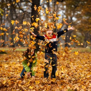 Girl and boy throwing up leaves in park